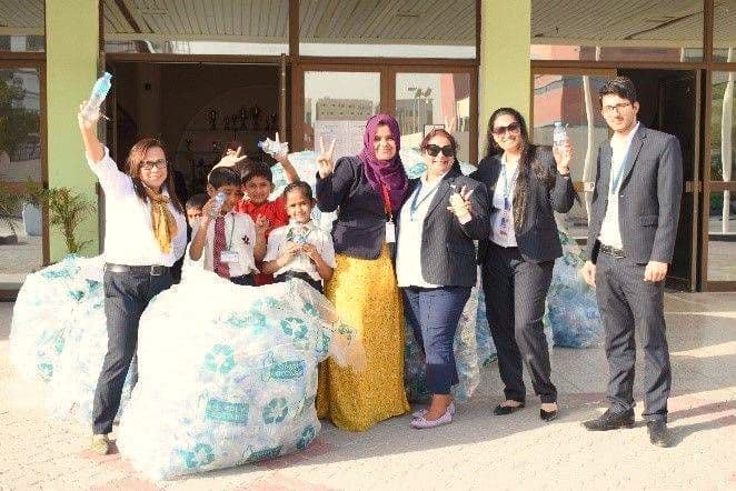 Students and teachers with large bags of cans collected for recycling