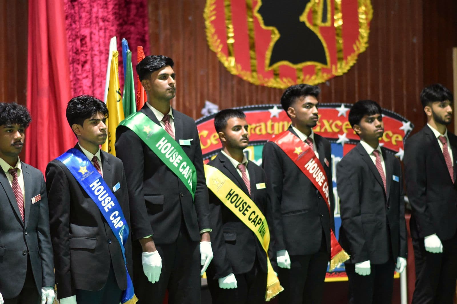 Student leaders in blazers and sashes on stage at the investiture