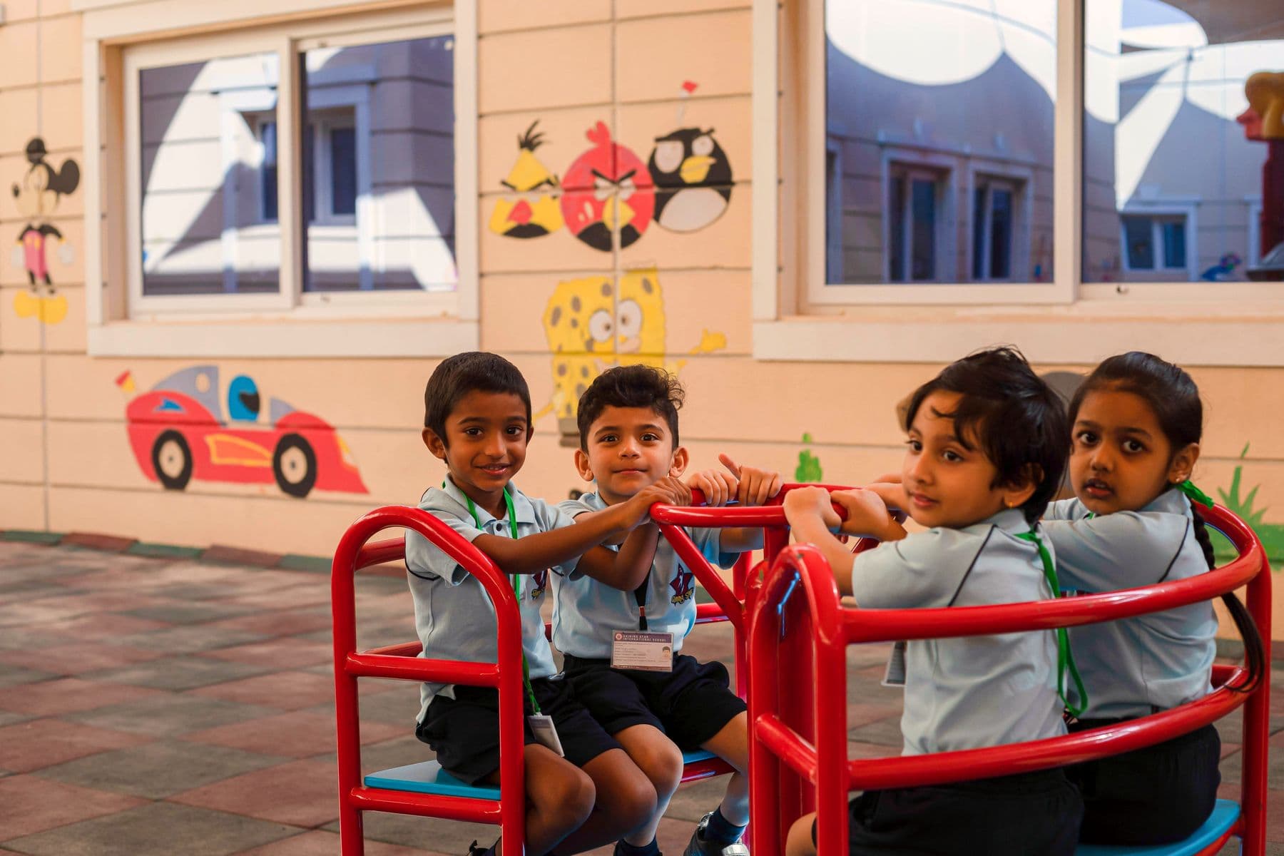 Four kindergarten pupils smiling from a red climbing frame