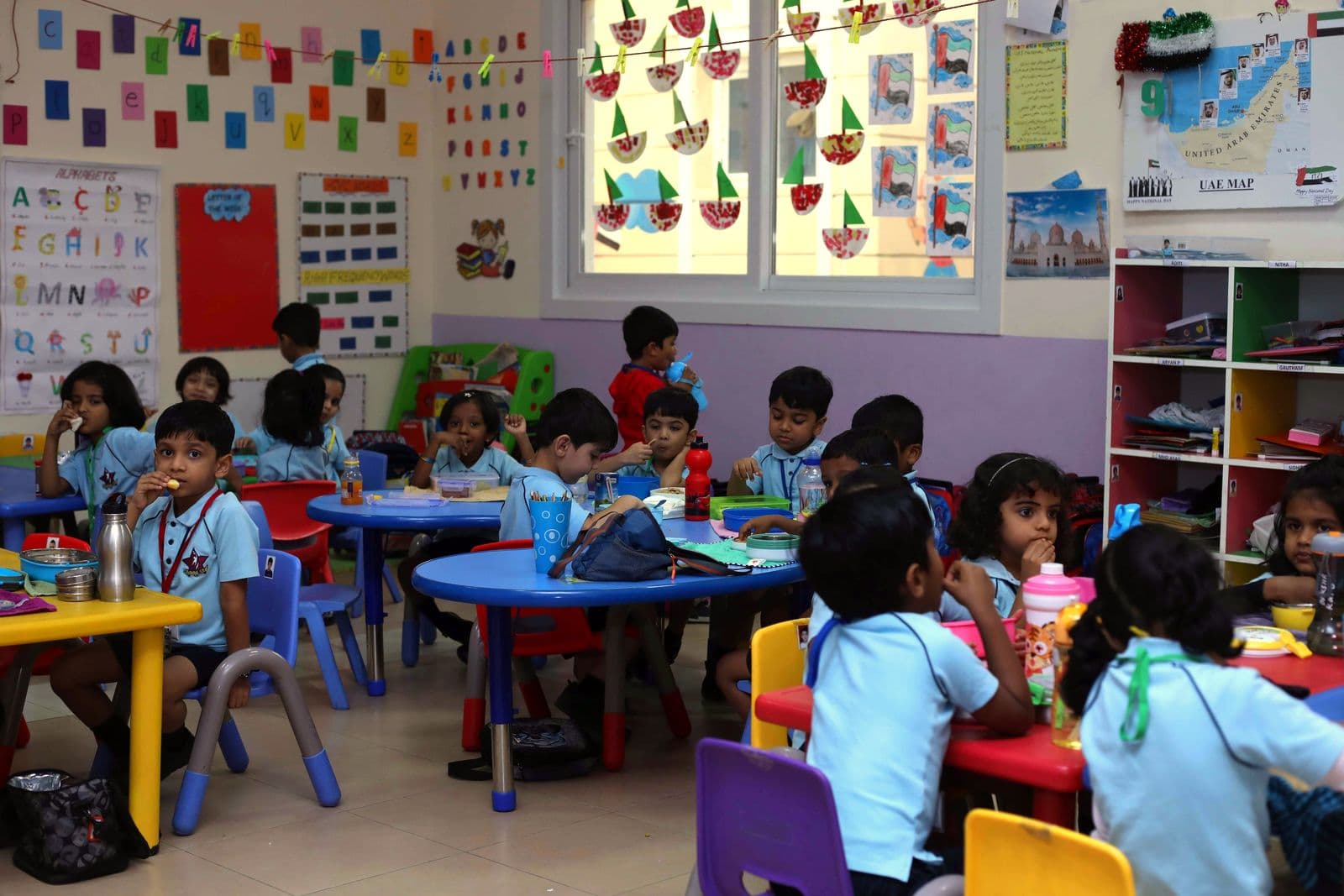 Kindergarten pupils having their snack together at round tables