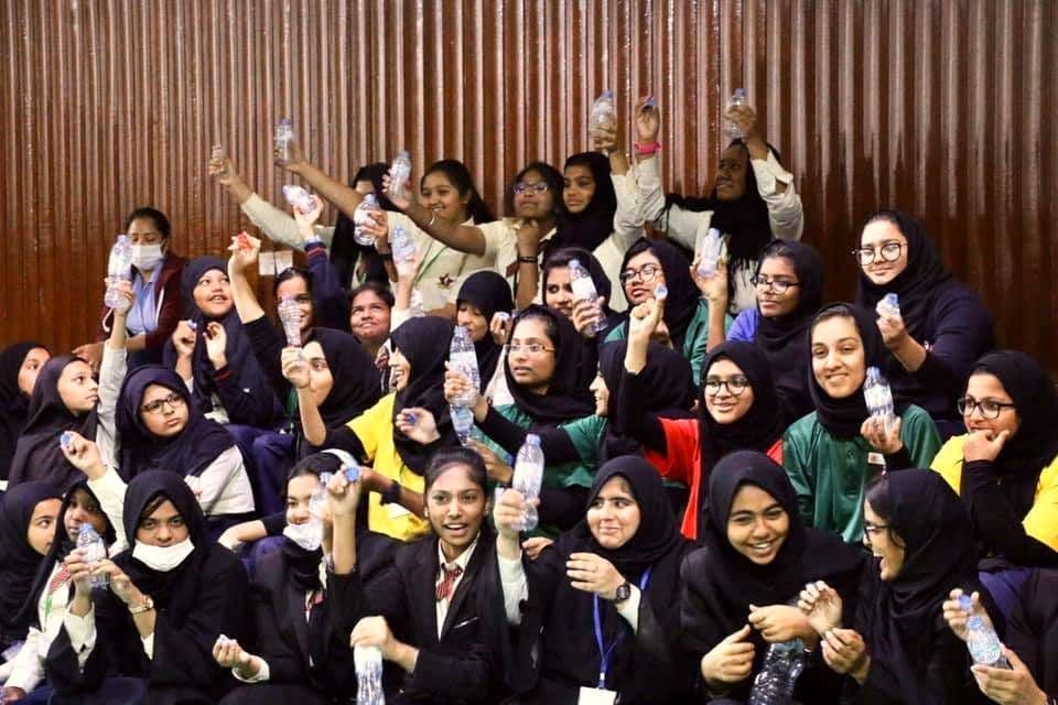 Secondary students cheering and holding up plastic bottles collected for recycling