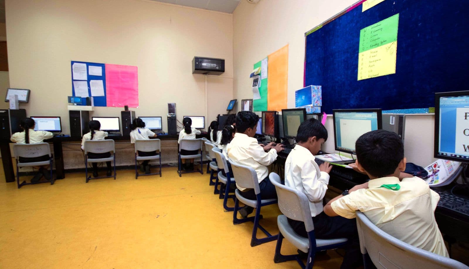 Pupils in white uniform shirts working at computers in the primary computer lab