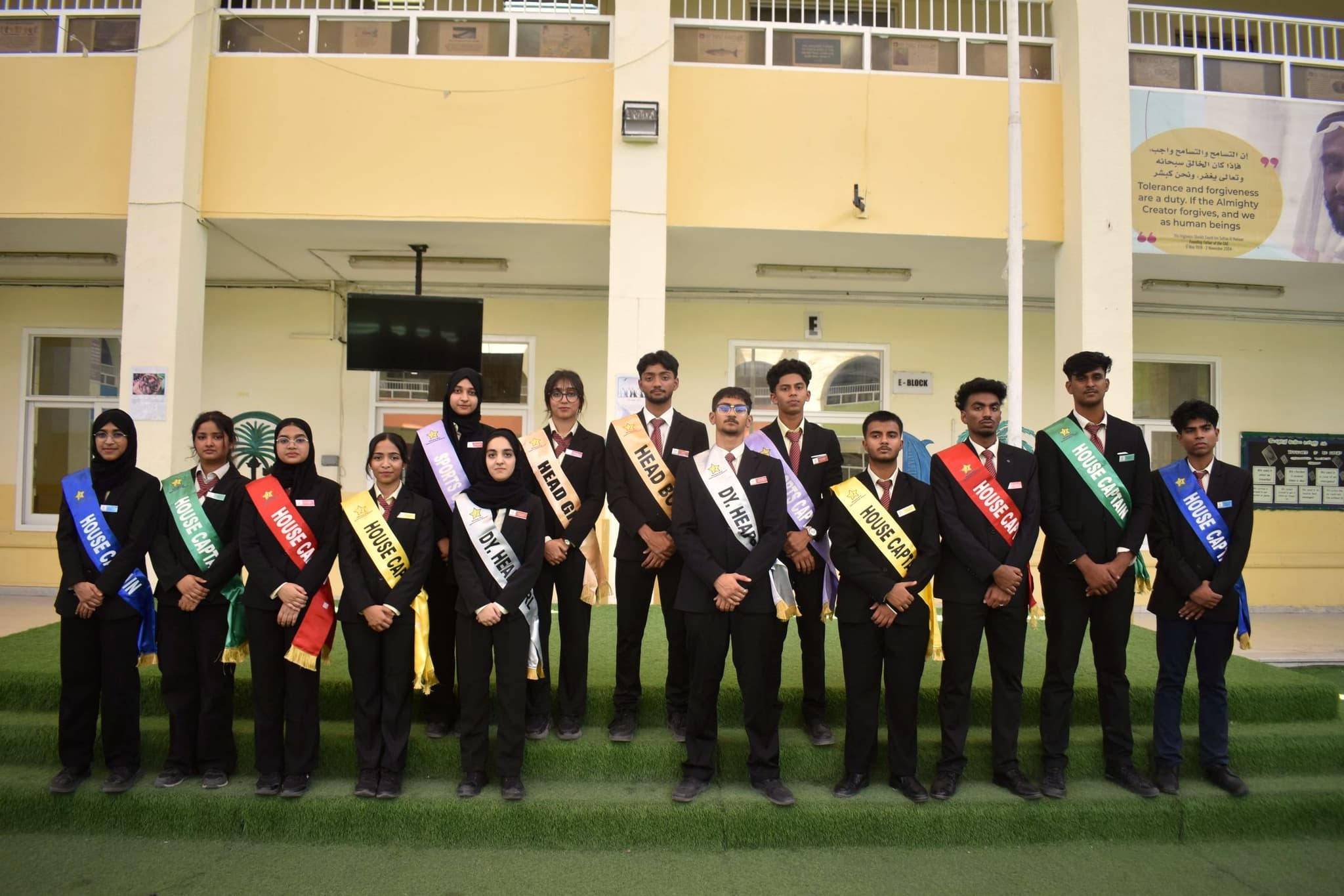 The 2025 Student Council in blazers and coloured sashes in the school courtyard