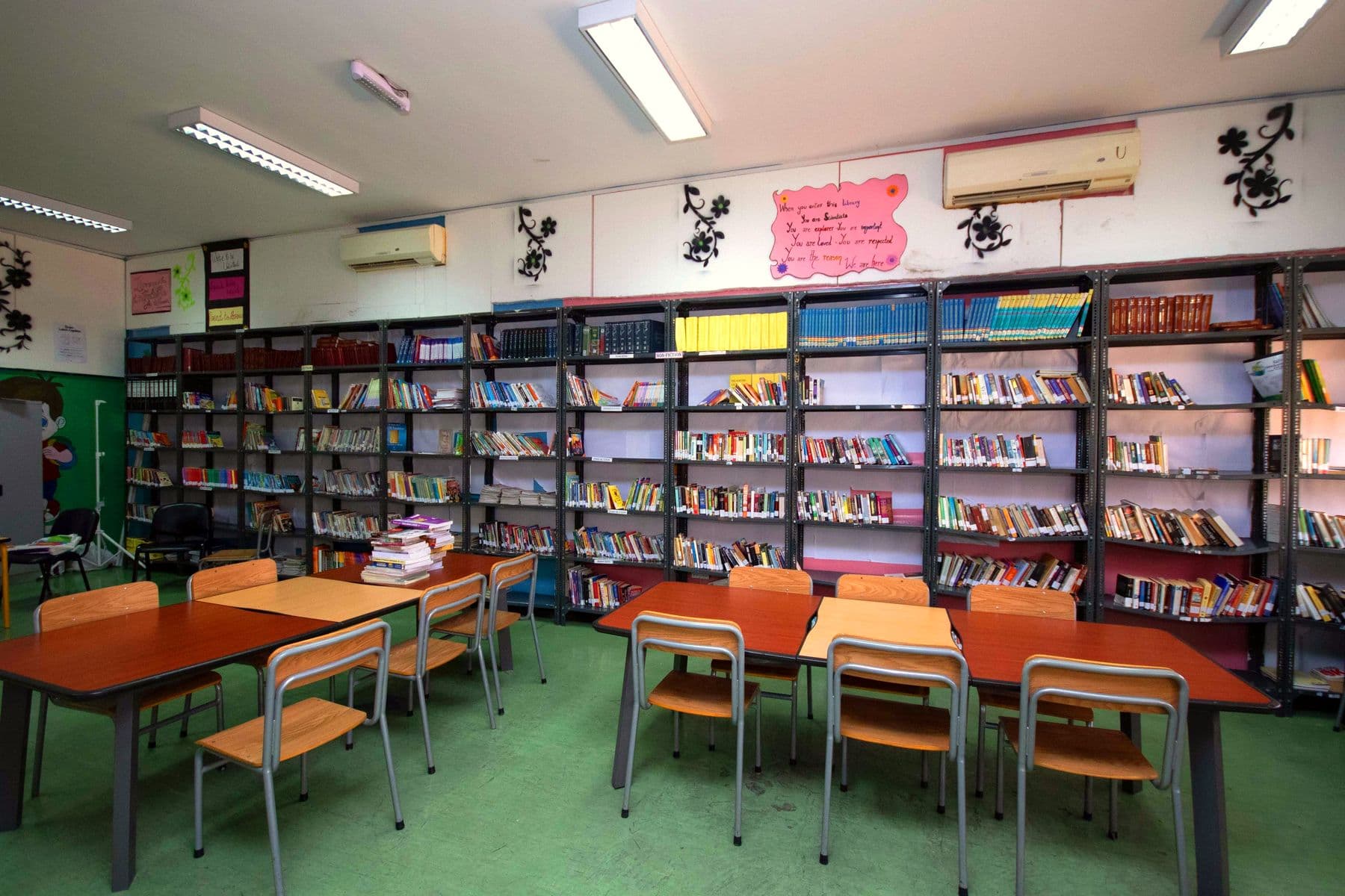 Tall shelves of books and wooden reading tables in the school library